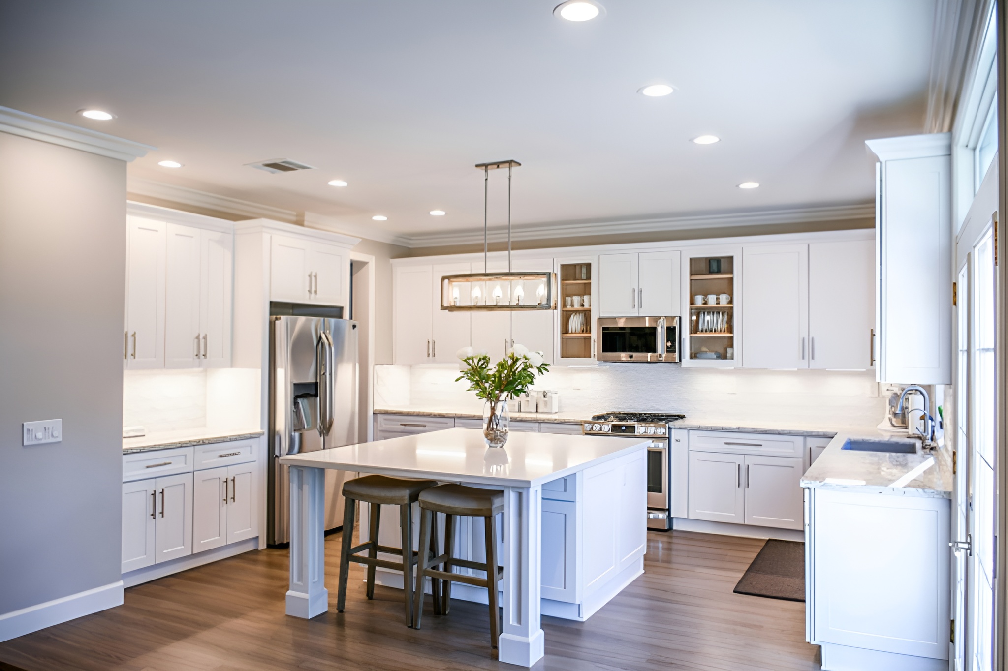 All-white shaker kitchen with white quartz island worktop, bar stools and stainless steel appliances — Inner Peace Interiors, Camberley