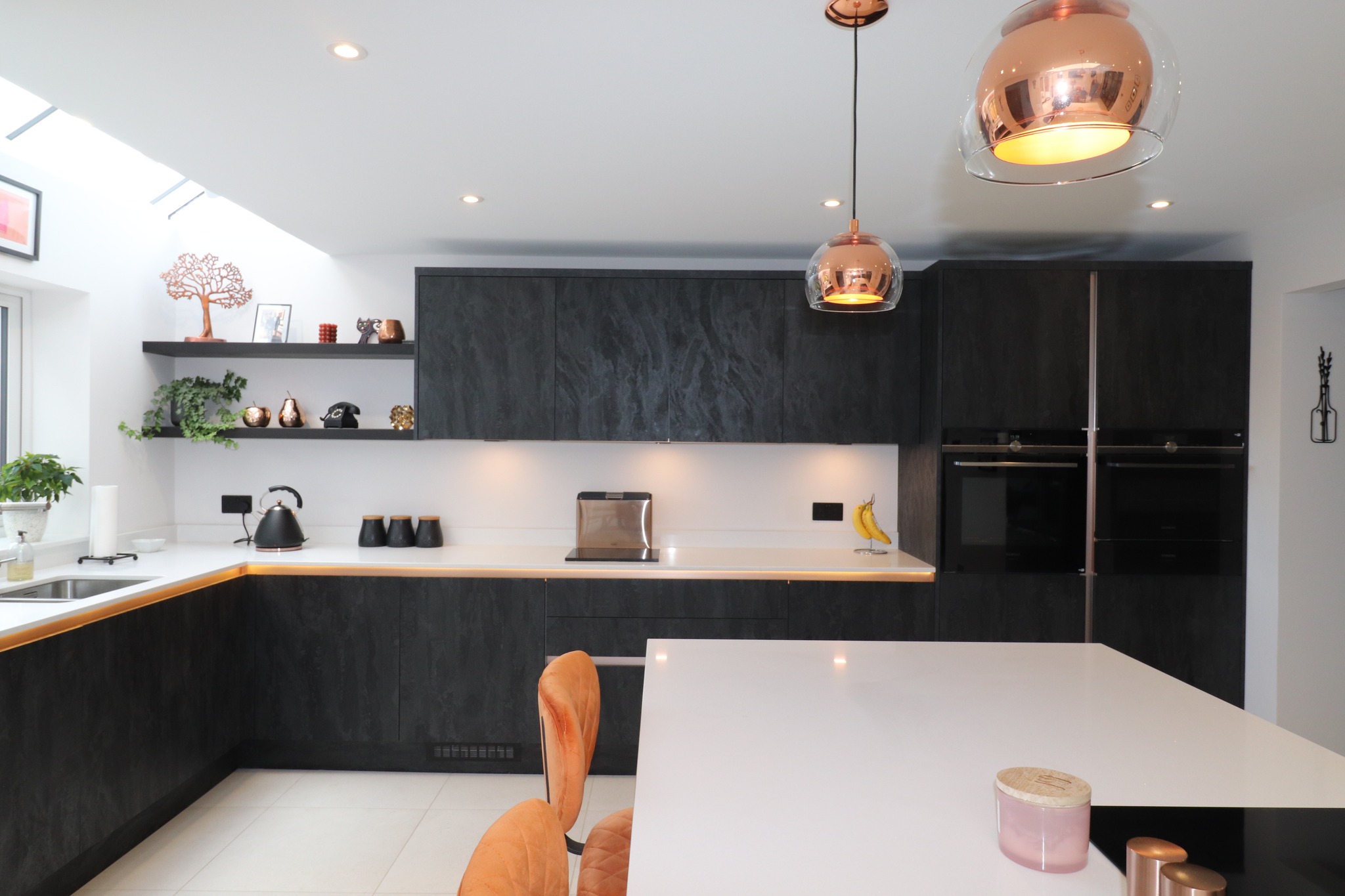 Dark modern handleless kitchen with white island, open shelving and copper pendant lights